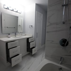 Bathroom renovation. White vanity and white and soft gray tiles on the walls and the floor. Built and designed by JK North York. Nov. 2018