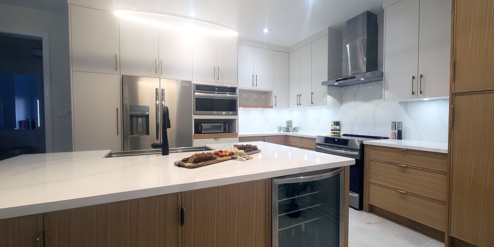 Custom made modern kitchen in Toronto Kitchen remodeling and renovation in Toronto- Two tone modern kitchen. Flat painted MDF in white and modern slim Shaker Oakwood cabinet doors. Quartz countertop and backsplash from LG Calacatta collection. Tall ceiling kitchen design. Design by JK 2023