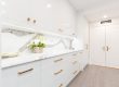 A sleek European modern kitchen with handleless, flat-panel cabinets in a matte white finish, a large marble island, and integrated high-end appliances, reflecting the sophisticated style popular in Toronto homes.