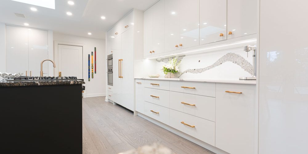 Modern white kitchen with a black island and gold hardware.