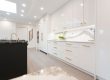 Modern white kitchen with a black island and gold hardware.