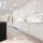 Modern white kitchen with a black island and gold hardware.