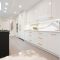Modern white kitchen with a black island and gold hardware.