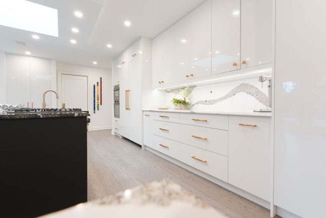 usersFfed afe da afffacdFlibraryFee c afc dbbbFA Edit Modern white kitchen with a black island and gold hardware.