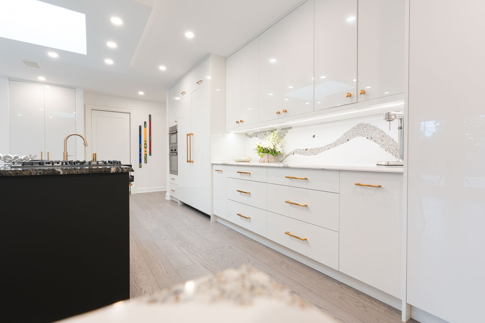 Modern white kitchen with a black island and gold hardware.
