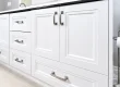 White bathroom vanity with brushed nickel hardware and black countertop.