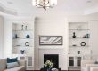 Modern living room with white built-in shelves, fireplace, and abstract art.