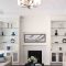 Modern living room with white built-in shelves, fireplace, and abstract art.