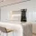 Modern white kitchen with marble island, bar stools, and wine fridge.