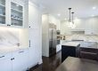 Modern white kitchen with a large stainless steel refrigerator and island.