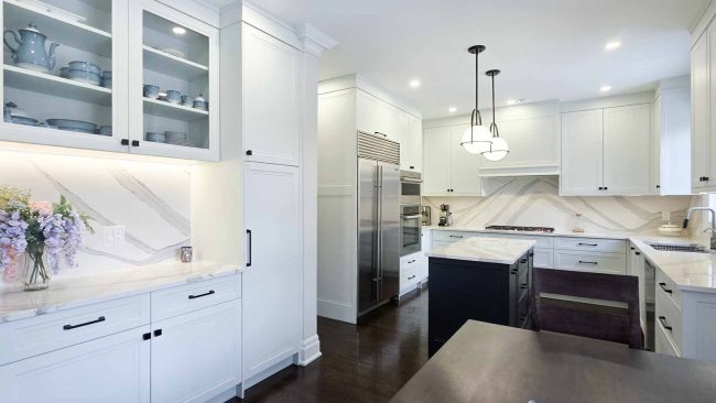 Modern white kitchen with a large stainless steel refrigerator and island.