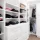 A well-organized white walk-in closet with shelves, drawers, and hanging clothes.