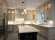 A spacious kitchen with light gray cabinets, a large island, and stainless steel appliances.