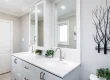 Modern white bathroom vanity with double sinks and a decorative tree wall art.