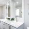 Modern white bathroom vanity with double sinks and a decorative tree wall art.